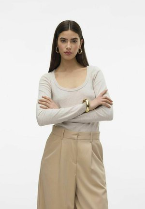 Ljusbeige långärmad topp med rundad halsringning, kombinerad med ljusbruna vida byxor. Slät textur, minimala sömmar och en avslappnad passform.