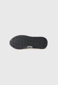 Black rubber outsole with square tread pattern; brown midsole, white upper with minimal detailing, sleek design.