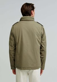 Olive green, lightweight jacket with a high collar, shoulder epaulets, and a straight cut. Smooth texture, minimal detailing, and no visible hardware.