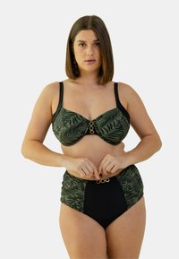 Haut de bikini à motif de feuilles de palmier vertes avec des accents noirs, présentant un détail en anneau doré, associé à un bas noir taille haute.