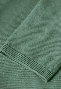 Tissu tricoté vert texturé avec une finition douce. Le design présente des accents côtelés et une apparence lisse et minimaliste.