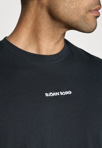 Black cotton t-shirt with a crew neckline, featuring a white embroidered "BJÖRN BORG" logo on the chest, smooth texture, and relaxed fit.