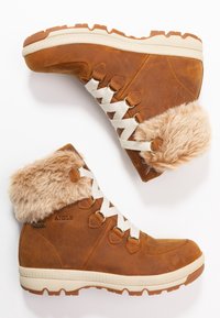 Bruine leren laarzen met een nepbonten kraag, witte veters, een gestructureerde rubberen zool en een logo detail. Voorzien van een schuine vormgeving voor extra ondersteuning.