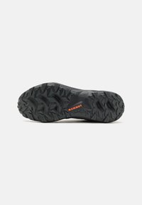 Semelle noire d'une chaussure de randonnée avec un motif de crampons texturé et agressif, et un détail du logo orange "MAMMUT".