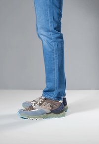 Sportsneaker mit einer Mischung aus Grau, Blau und Grün, Mesh-Akzenten, strukturierten Materialien und einem klobigen Sohlen-Design.