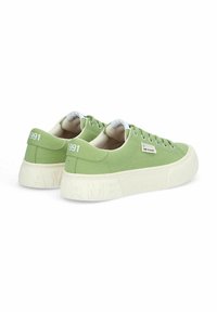 Sneakers in tela verde con suola spessa color crema, caratterizzati da un logo cucito, una linguetta sul tallone e un design con lacci. Numero di modello "1991" visibile sul retro.
