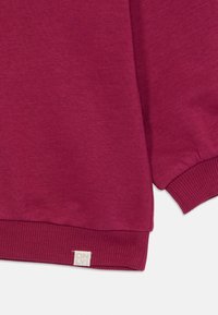 Burgundy sweatshirt med ribbad mudd och nederkant. Mjukt, strukturerat tyg. Litet märke med "ONLY" placerat vid den nedre sömmen.