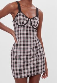 Svart och röd rutig klänning med formade kupor, tjocka svarta remmar, en figursydd bodice och rynkade sidodetaljer. Slät tygtextur.