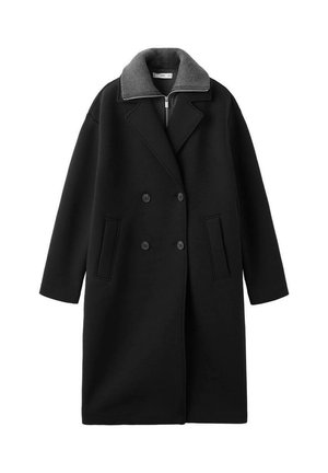 Long manteau noir croisé avec deux poches avant et un col haut gris en maille côtelée avec une fermeture éclair en dessous.