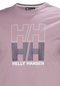 Světle fialové bavlněné tričko se silným logem "HH" a textem "HELLY HANSEN" v bílé barvě. Klasický kulatý výcut, hladká textura, volný střih.
