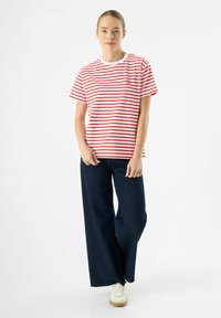 Rood-wit gestreept T-shirt van katoen, ronde hals, korte mouwen, gecombineerd met donkerblauwe wijde jeans en witte sneakers.