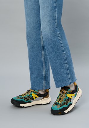 Multicolored sneaker featuring black, teal, yellow, and brown accents. Durable fabric, textured details, and a chunky white sole.