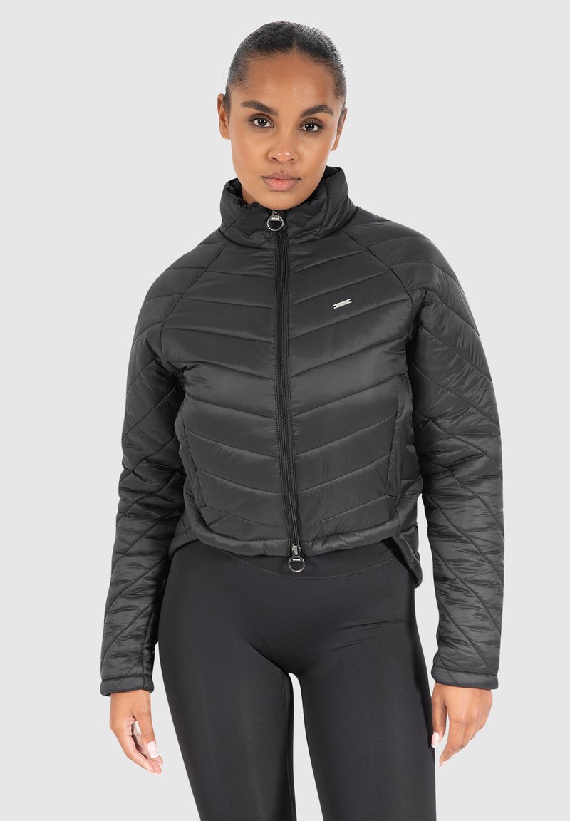 Chaqueta acolchada negra con un alto cuello, cierre de cremallera frontal y un patrón de acolchado diagonal. Cuenta con un pequeño logo en el lado izquierdo del pecho.