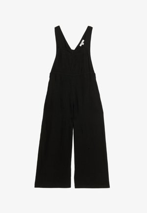 Zwart overall jumpsuit gemaakt van zachte stof, met wijde benen, een diepe V-hals en verstelbare bandjes. Geen opvallende patronen of hardware.