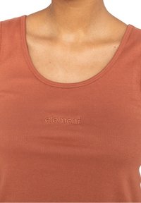 Débardeur couleur rouille en tissu côtelé, muni d'un col rond et d'un logo brodé discret sur la poitrine.