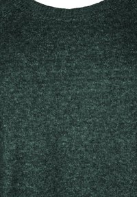 Maglione lavorato a maglia verde scuro con scollo rotondo. La texture appare morbida e leggermente maculata, con un motivo uniforme e senza chiusure visibili.