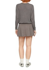 Haut gris à manches longues avec un léger éclat. Assorti à une jupe plissée gris foncé avec de fines rayures blanches et des chaussures argentées.