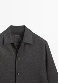 Szara koszula na guziki wykonana z teksturowanej tkaniny, z kołnierzem typu spread i dwoma przednimi guzikami. Metka widoczna poniżej kołnierza.