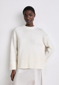 White knitted sweater with ribbed hem and cuffs. Boxy design and crew neckline, featuring a soft texture.