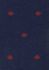Chaussettes navy avec une texture côtelée ornées de points rouges uniformément espacés, offrant un motif contrasté sur le fond sombre.