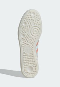 Adidas sneakersula i krämfärgad gummi med texturerad mönster, som har cirkulära och vågiga design, samt en logotyp i centrum.