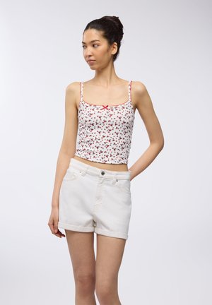 Top corto con stampa floreale bianca e accenti rossi, decorato con un fiocco. Abbinato a pantaloni shorts in denim bianco a vita alta con risvoltini e tasche frontali.