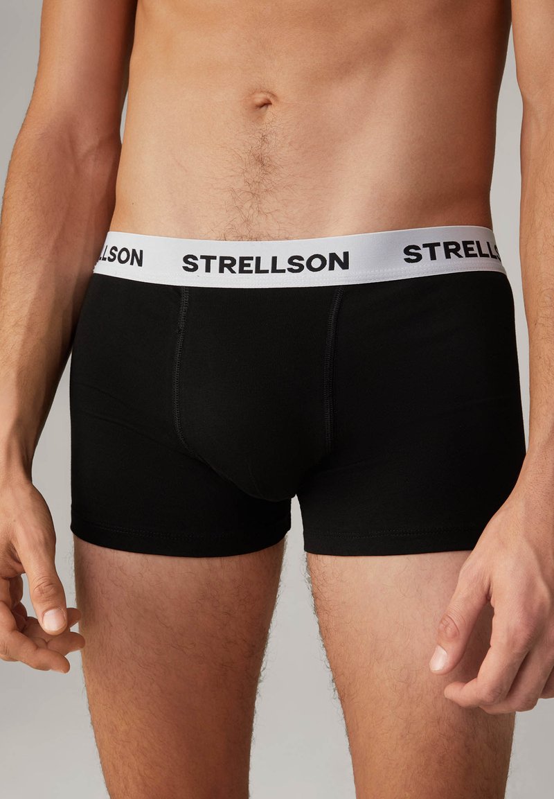 Zwarte boxershorts van zacht materiaal met een witte elastische tailleband waarop het logo 'STRELLSON' in het zwart is gedrukt. Sluiting passend ontwerp.