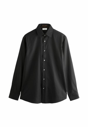 Zwarte langemouwshirt van katoen. Heeft een puntige kraag, acht knopen aan de voorkant en een rechte zoom met knoopmanchetten.