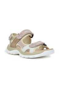 Sandalias ligeras con una combinación de colores marrón claro y blanco, con correas ajustables y una suela de goma texturizada para mayor tracción. Diseño de punta abierta.