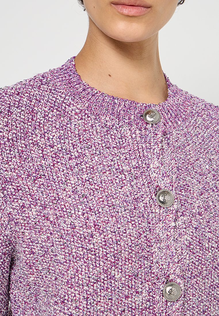 Lila strukturierte Strickjacke mit Rundhalsausschnitt, versehen mit silbernen Knöpfen vorne in der Mitte und einer gestrickten Optik.