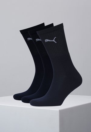 Trois paires de chaussettes bleu marine, fabriquées dans un matériau doux, avec une texture côtelée et un logo Puma blanc sur la bordure.