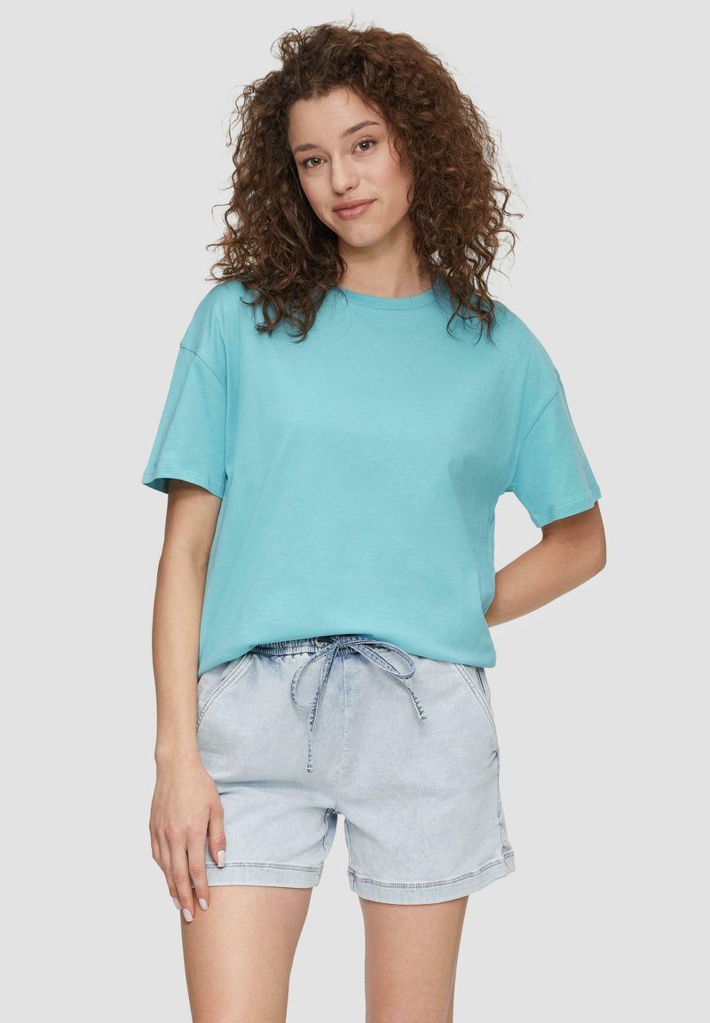 Turkusowa bawełniana koszulka z krótkim rękawem, zestawiona z jasnoniebieskimi szortami dżinsowymi z elastycznym paskiem w talii i sznurkiem.