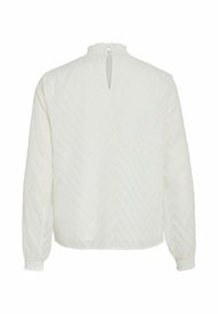 Weiße Bluse mit langen Ärmeln, strukturiertem Chevron-Muster, gerafftem Ausschnitt und kleiner Schlüsselöffnung hinten. Gummizug an den Ärmelabschlüssen.