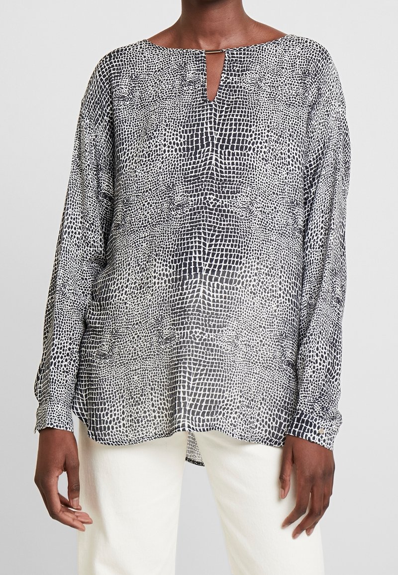 Czarna i biała bluzka z długim rękawem o subtelnym wzorze skóry węża, z wycięciem przy szyi i luźnym krojem.