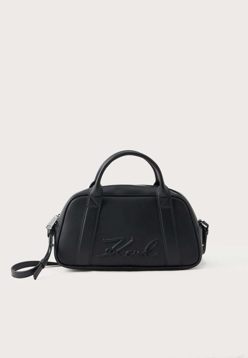 Sac à main en cuir noir avec doubles poignées supérieures, une bandoulière détachable et le logo embossé "Karl" sur le panneau avant.