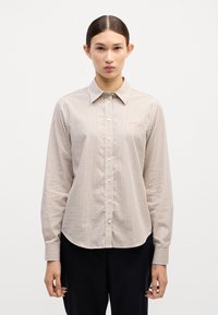 Smeđi i bež kockasti longsleeve s majicom sa dugmadi, ovratnikom i manžetama. Tkanina izgleda glatko i ima oštar završetak.