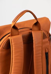 Leder-Rucksack in verbranntem Orange mit gepolsterten Schultergurten, Tragegriff oben und einer eleganten Reißverschlusstasche an der Seite. Gesticktes Logo-Detail.