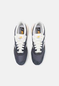 Baskets bleu et gris avec un dessus en mesh et en daim, lacets blancs et semelle intermédiaire de couleur crème. Logo visible sur la languette.