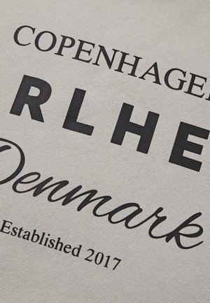 Material gri deschis cu text negru îndrăzneț: „COPENHAGEN”, „RLHE”, „Danemarca” și „Înființat în 2017”. Textură netedă, design casual.