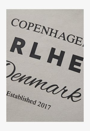 Helehall kangas julgete mustade tähtedega: "COPENHAGEN", "RLHE", "Denmark" ja "Asutatud 2017." Sile tekstuur, vabaaja stiil.
