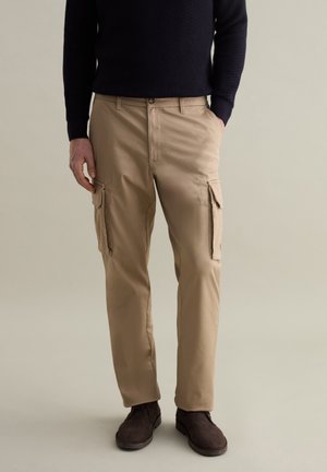 Beige Cargo-Hosen mit geradem Schnitt, ausgestattet mit Seitentaschen, einem Knopf- und Reißverschluss sowie einer glatten, strapazierfähigen Stofftextur.