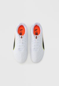 Hvite fotballsko med en teksturert overflate, med svarte og neon gule detaljer, og en lys oransje innerfôr. Inkluderer lisser og merkevare.