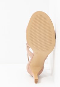 Chaussure à talon avec une tige en daim rose pâle, bout pointu et talon fin. Semelle beige texturée avec un motif nervuré pour une bonne adhérence. Taille 37 indiquée.