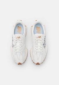 Des chaussures de sport blanches avec un design texturé, ornées d'une touche de motif léopard, fermeture à lacets, et une doublure bleu clair. Semelles en caoutchouc.