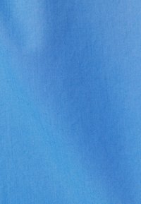 Helleblaue Stoff mit glatter Textur und leicht glänzender Oberfläche. Das Material scheint leicht und gleichmäßig in der Farbton zu sein.