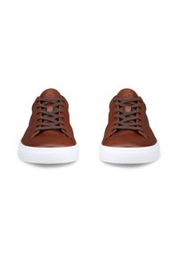 Paire de baskets en cuir marron avec des lacets foncés et des semelles en caoutchouc blanches, vues de face sur fond blanc.