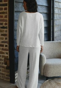 Hellgraues Loungewear-Set mit geripptem Textur, oversized langen Ärmeln und weiten Hosen. Weicher Stoff und lockere Passform für hohen Tragekomfort.
