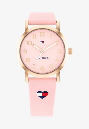 Pink silicone watch with a gold-colored stainless steel case, clear numeric markers, and a heart-shaped logo on the strap.