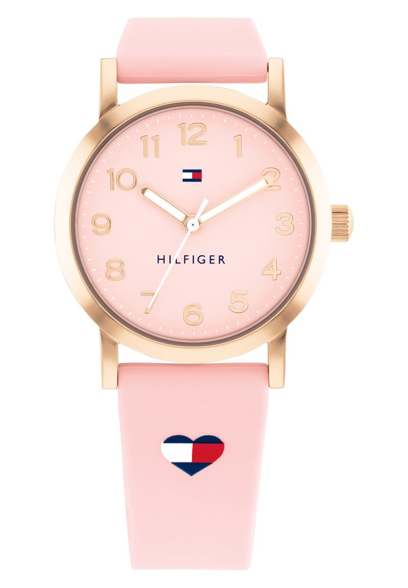 Rosa silikonklocka med ett guldfärgat rostfritt stålhus, klara siffror och en hjärtformad logotyp på remmen.