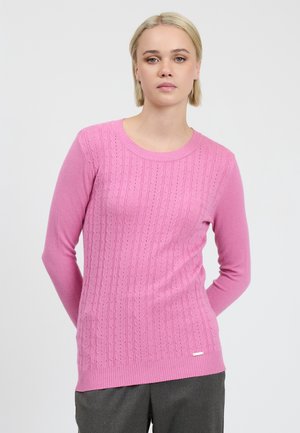 Suéter de punto rosa que presenta una textura acanalada, cuello redondo y mangas largas. Incluye detalles de costura decorativa y un pequeño acento de logo.